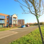 Modern residential building with parked cars and trees