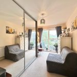 Modern bedroom with mirrored wardrobe and window view.