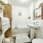 Modern bathroom with sink, bathtub, and towels.