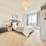 Modern bedroom with double bed and natural light.
