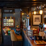 Cosy pub interior with coffee sign and snacks display.