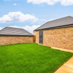 Brick garage with green lawn and wooden fence.
