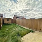 Back garden with wooden fences and cloudy sky.