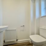 Small modern bathroom with white fixtures and window.