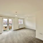Spacious room with large windows and neutral decor.
