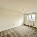 Empty room with carpet and window, neutral walls.