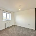 Empty room with window, carpet, and bulb light.