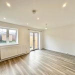 Bright empty room with wooden flooring and windows.