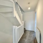 Modern staircase with white bannisters and grey carpet.
