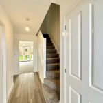 Bright hallway with stairs and garden view.