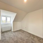 Empty attic room with window and radiator.