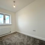 Empty small bedroom with grey carpet and window