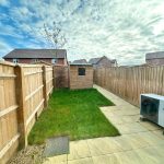 Fenced garden with small shed and heat pump.