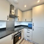 Modern kitchen with white cabinets and appliances.