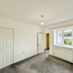 Empty room with window and grey carpet floor.
