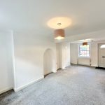 Spacious living room with carpet and natural light.