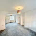 Spacious modern room with grey carpet and white walls.