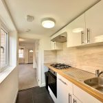 Modern narrow kitchen with white cabinets and appliances.