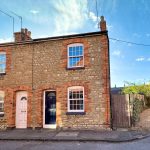 Charming terraced house with brick facade, sunny day.