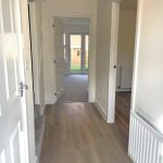 Bright hallway leading to carpeted living area.