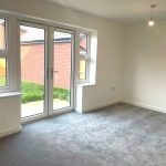 Empty room with grey carpet and garden view.