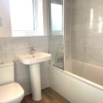 Modern bathroom with tiled walls and white fixtures.