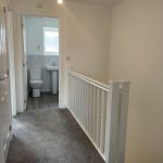 Bright hallway with bathroom at end.