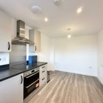 Modern kitchen with oven and wooden flooring.