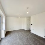 Spacious empty living room with carpet and large window.