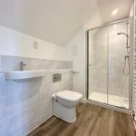 Modern bathroom with shower, sink, and wooden floor.