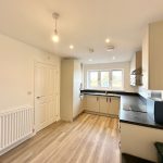 Modern kitchen with wooden floor and white cabinets.