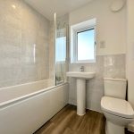 Modern bathroom with bathtub, sink, and toilet.