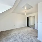 Empty loft room with carpet and mirrored wardrobe.