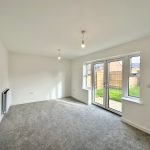 Bright empty room with carpet and garden access.