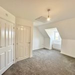 Empty room with grey carpet and white walls.