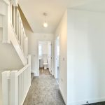 Bright hallway with staircase and small bathroom.