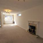 Spacious living room with fireplace and front door.