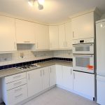 Modern kitchen with white cabinets and appliances.