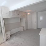 Spacious white bedroom with fitted wardrobes and mirror.
