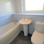 Modern bathroom with bathtub, sink, and toilet.