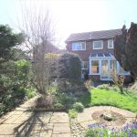 Sunny garden with house and patio view.