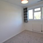 Small bedroom with checkered curtains and grey carpet.