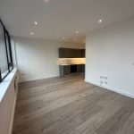 Modern apartment with wooden flooring and large windows.