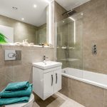 Modern bathroom with beige tiles and green plant.