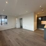 Modern flat interior with large windows and kitchen.