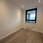 Small modern room with large window and wooden floor.