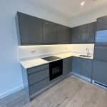 Modern grey kitchen with integrated appliances and wooden floor.