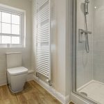 Modern bathroom with shower, toilet, and window.