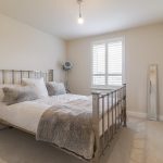 Bright bedroom with metal bed frame and large window.