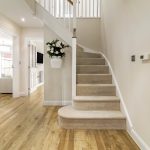 Modern hallway with wooden floor and carpeted stairs.